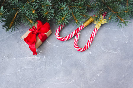 Gift boxes with red bows, caramel sticks and fir branches on concrete background. copyspace. Christmas and New Year concept. postcard.の写真素材