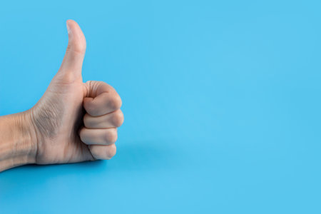 Hand with thumbs up on a blue background close up. copyspace.の写真素材