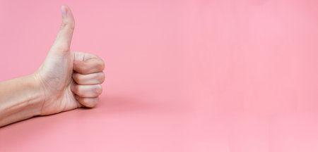 Hand with thumbs up on a pink background close up. copyspace. Banner.の写真素材