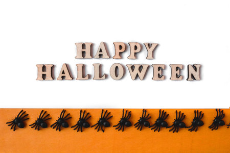 Happy Halloween lettering. Flatly on an orange and white background. copyspace. Spiders in a row.の写真素材