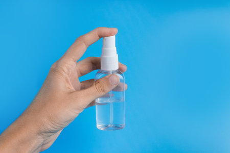 A woman's hand with an antiseptic on a blue background close-up. The concept of hygiene and cleanliness. Disinfectant.の写真素材