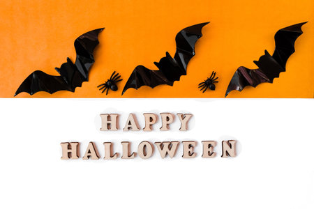 Happy Halloween lettering. Flatly on an orange and white background. copyspace. Bats and spiders in a row.の写真素材