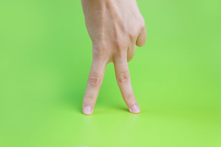 Women's fingers walking on a green background.の写真素材