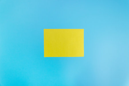 Mock up of a blank yellow sheet on a blue background. Paper template for design. business card. Flat lay, copy space.の写真素材
