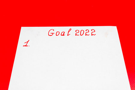 List of New Year's goals for 2022 on a piece of paper, handwritten on a red background. Planning, motivation, business ideas for the new year. copyspace.の写真素材