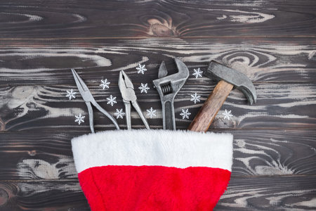 Flat composition with construction tools in santa claus hat on wooden background. The concept of New Year and Christmas in the construction industry. top view. flatly.の写真素材