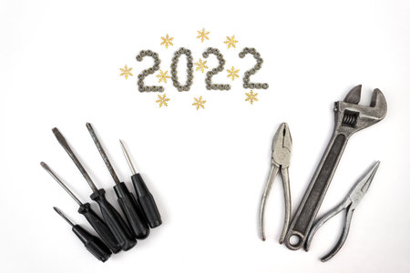 Carpentry tools on a white background with 2022 lined with screw nuts. The concept of New Year and...