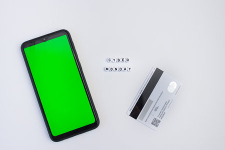 Cyber monday lettering with smartphone with green screen and payment card on white background. Online shopping concept. Chrome key. Mock up.の写真素材