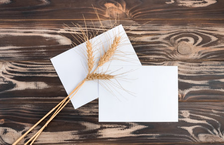 Mock up of a blank sheet on a dark wood background with a spikelet. Paper template for design. business card. Flat lay, copy space.の写真素材