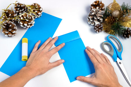 How to make a christmas snowflake from colored paper and glue with your own hands. DIY concept. Step by step giude. Step 6. Fold one half in half twice to the center line of the fold.の写真素材