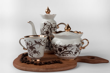 Tea set: cup, coffee pot and sugar bowl with coffee beans on a wood surface, white background.の写真素材