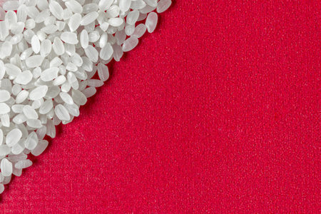 Grains of rice grit on a red background. A healthy diet. Space for text.の写真素材