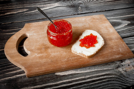 Red salmon caviar in a jar and on a butter sandwich.の写真素材