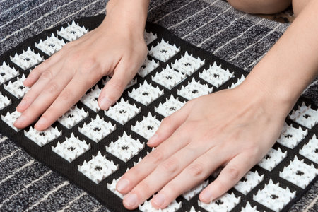 Massage of female hands on an acupuncture mat. acupressure treatment. alternative medicine concept.の写真素材