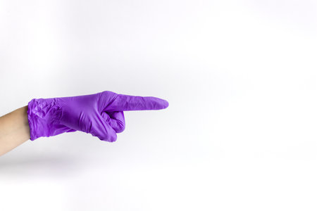 Hand in medical glove with finger pointing to the side on a white background. A place for text.の写真素材