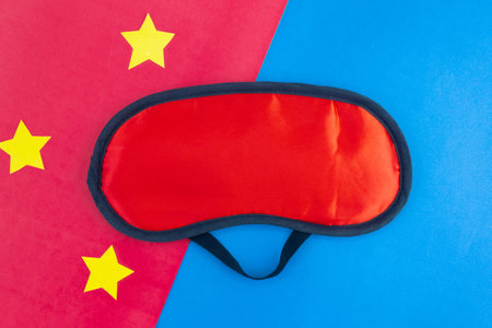 Red sleep mask on a pink blue background. Healthy sound sleep concept.の写真素材