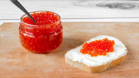 Red salmon caviar in a jar and on a butter sandwich.の写真素材