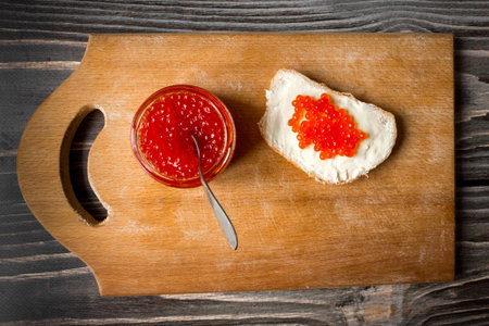 Red salmon caviar in a jar and on a butter sandwich. top view.の写真素材