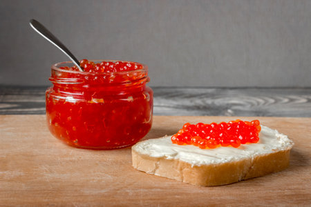 Red salmon caviar in a jar and on a butter sandwich.の写真素材