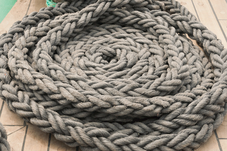 Gray sea rope, folded in a circle close-up on the ships deck.の写真素材