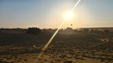 A sunset in the Deserts of Thar, India. Just as the sun is going down we can see a person paragliding in the distance.の写真素材