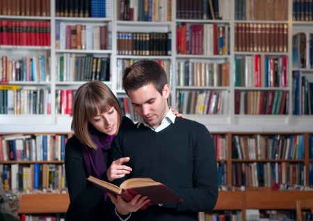 Couple of students at the library reading a bookの写真素材