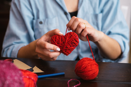 Woman creating red woolen heartの写真素材