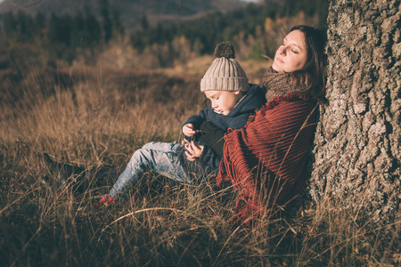Mother and son sitting under the tree.の写真素材