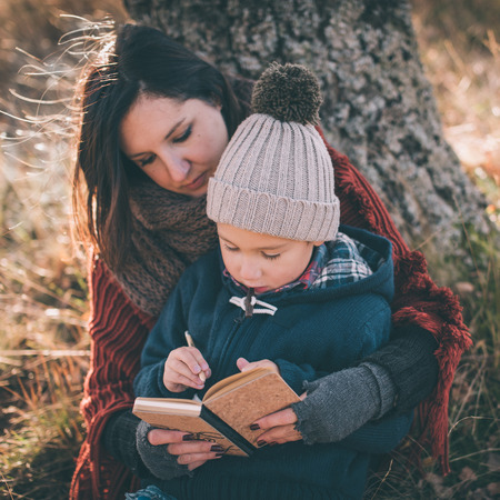 Mother helping her son writing first lettersの写真素材