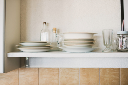 White shelf with plates, glasses and jarsの写真素材