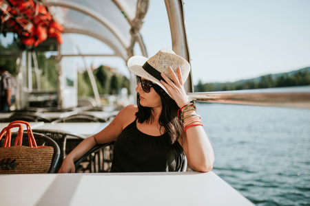 Woman in hat enjoying beautiful day on the lakeの写真素材