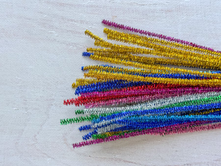 Bundle of colorful metallic pipe cleaners in gold, red, blue, green, pink, and silver shades placed...