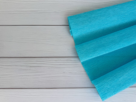 Bright light blue crepe paper roll placed on white wooden background, ideal for creative projects, and handmade crafts.の写真素材