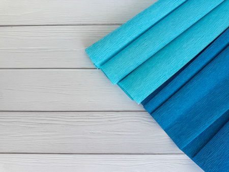 Rolls of crepe paper in light and dark blue shades placed diagonally on white wooden surface, perfect for DIY crafts and paper decorations.の写真素材