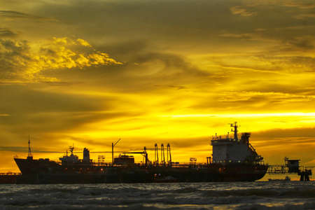 PORT DICKSON, MALAYSIA : Silhouette. Selective focus. Sunset at the beach with Cargo Ship and beautiful yellow sky on November 10, 2017.のeditorial素材