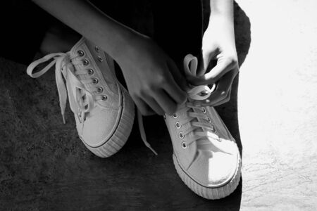 Black and white. The hand is tying a shoelaceの写真素材