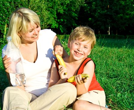 Portrait of the happy beautiful young woman-blonde with the laughing child on picnic. の写真素材