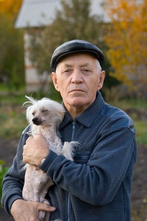 Portrait of the elderly man with a dog of breed chinese crested against the natureの写真素材