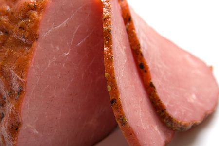 Piece of a ham with the cut chunks on a white background. Isolated
