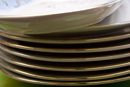 Pile of pure plates with a golden fringing on a green background