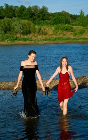 Two young beautiful girls in water of river against summer landscapeの写真素材