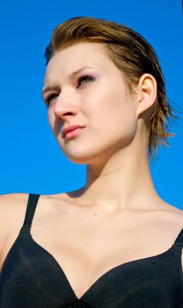 The young girl in black bra against blue summer skyの写真素材
