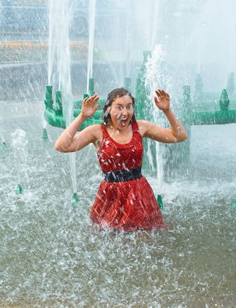 The young laughing girl in wet clothes in a city fountainの写真素材