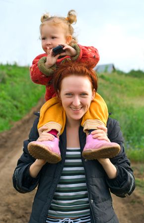 Young women with a little child on hands agaist summer nature. Shallow DOF, focus on face of womenの写真素材