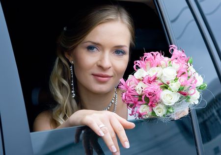 serenity bride with flower bouquet siting in the car. Shallow DOF, focus on flowersの写真素材