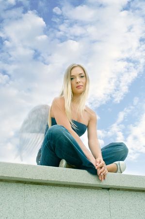 sad lovely angel against blue cloudy skyの写真素材
