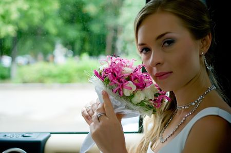 Portrait of young beautiful bride with flowers in car. Shallow DOFの写真素材