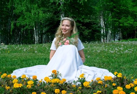 The portrait of the happy smiling bride in a white wedding dress with a bunch of flowers in parkの写真素材
