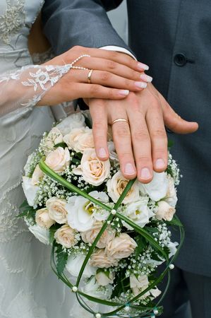 Hands of a newly-married couple on flower bouquetの写真素材