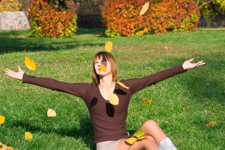 The young girl in autumn park during a leaf fallの写真素材